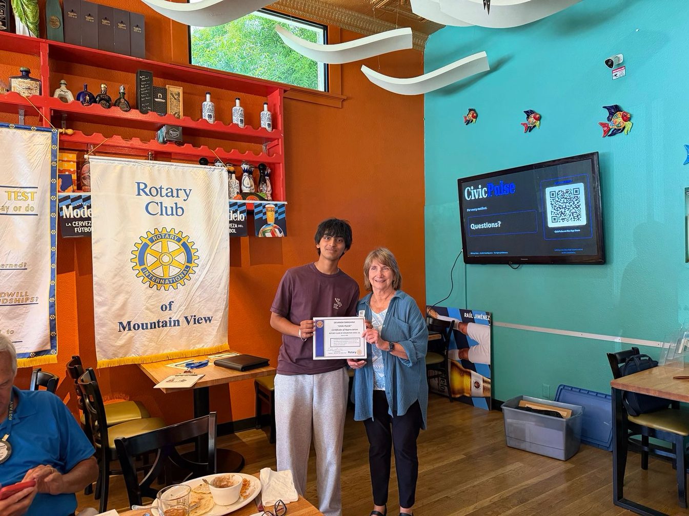 Devansh receiving a Certificate of Appreciation for CivicPulse from the Rotary Club of Mountain View, with CivicPulse shown on the screen behind.
